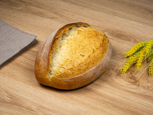 Artisan round bread on wooden surface with wheat
