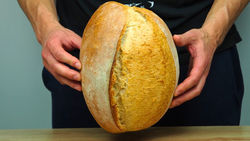 Mariusz Lasak holding a freshly baked artisan bread loaf