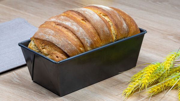 Homemade bread in loaf pan with wheat decoration